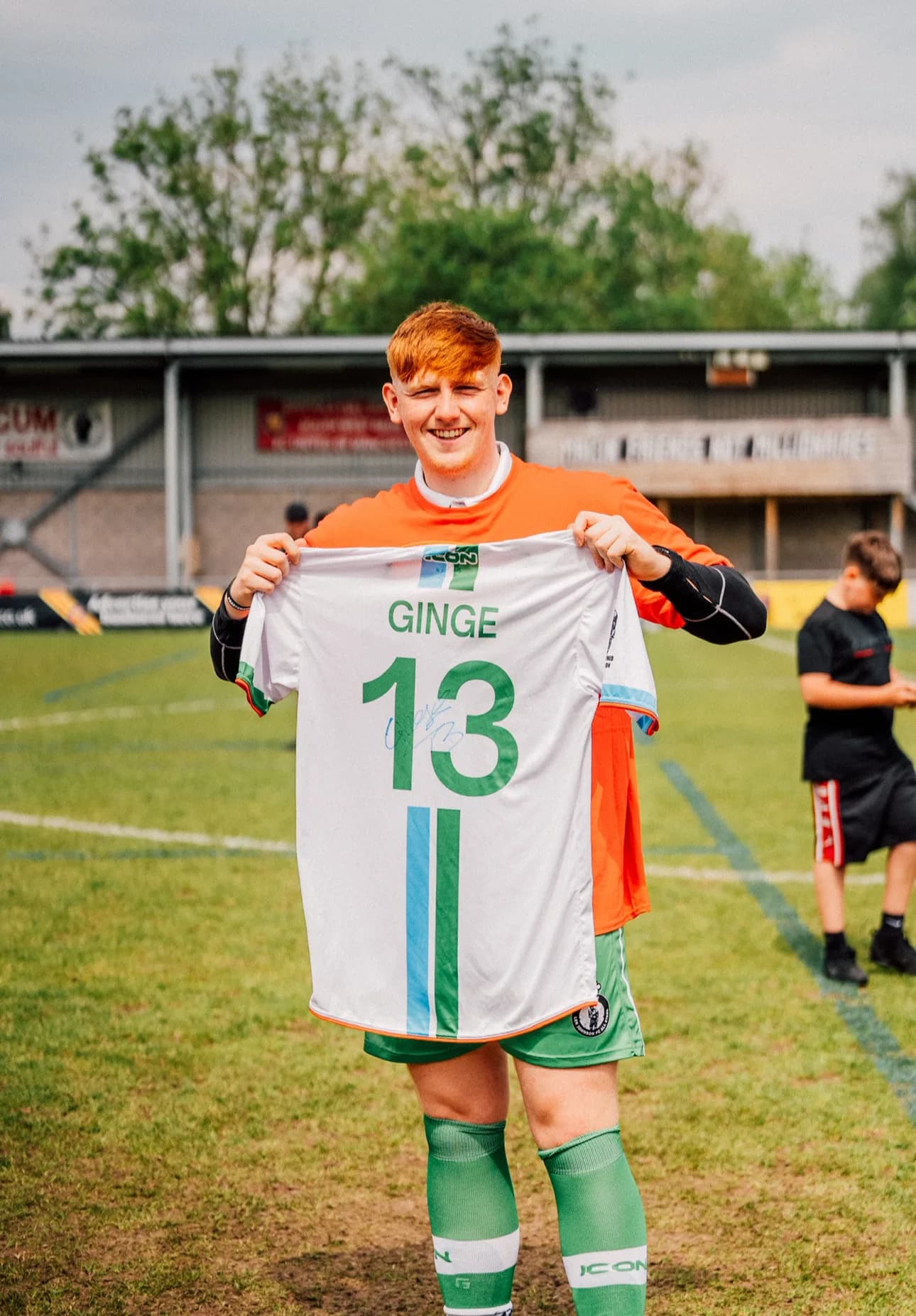 YouTuber Angry Ginge holds up a signed matchday shirt printed GINGE 13