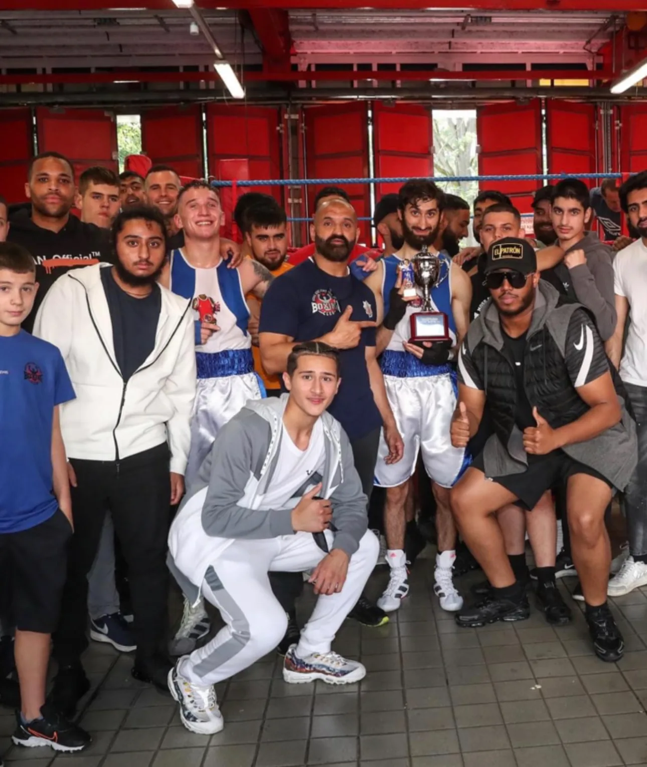 The Moss Side Fire Station Boxing Club team pose together holding the Len Johnson Cup trophy