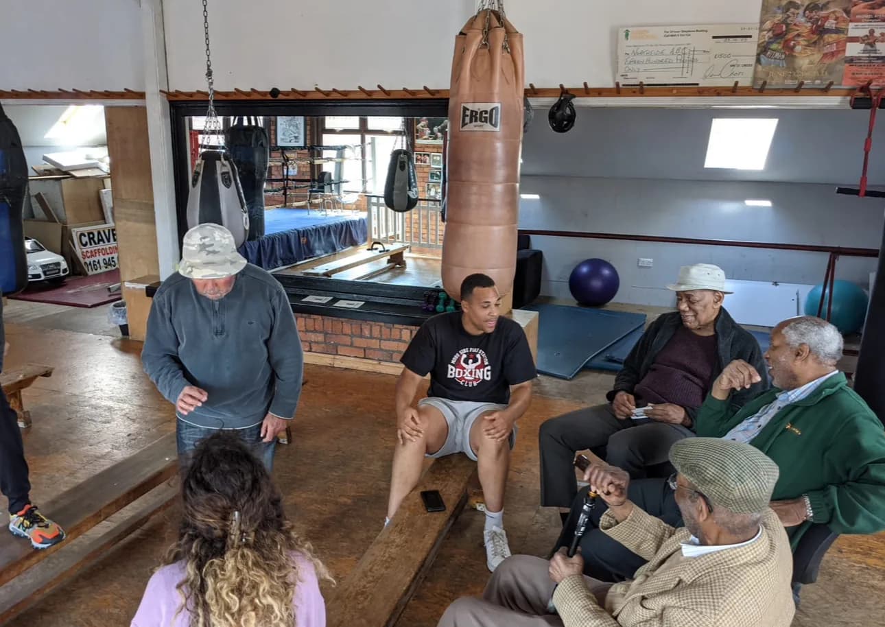 Campaign members in conversation with community elders in a Manchester boxing gym