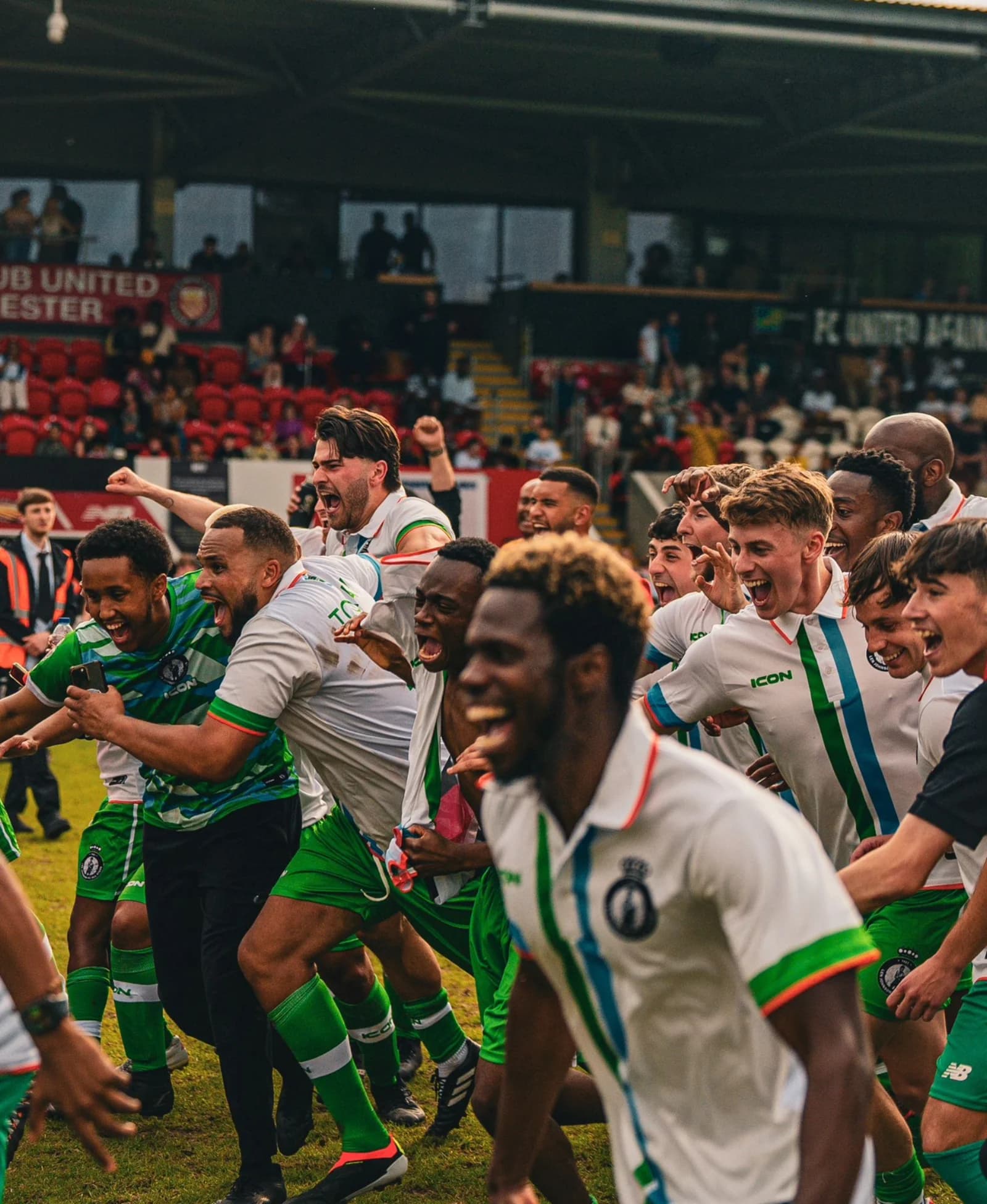 Players celebrate together, arms raised, running across the pitch