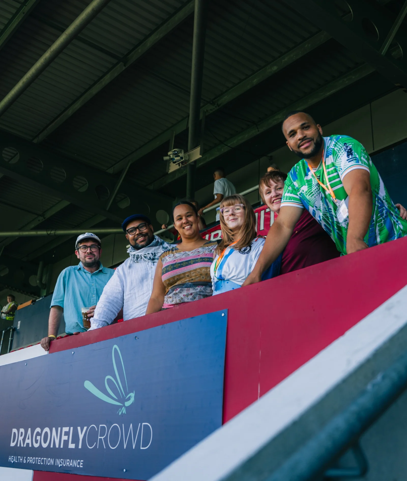 A group of supporters lean over the stand barrier, branded Dragonfly Crowd, during the match