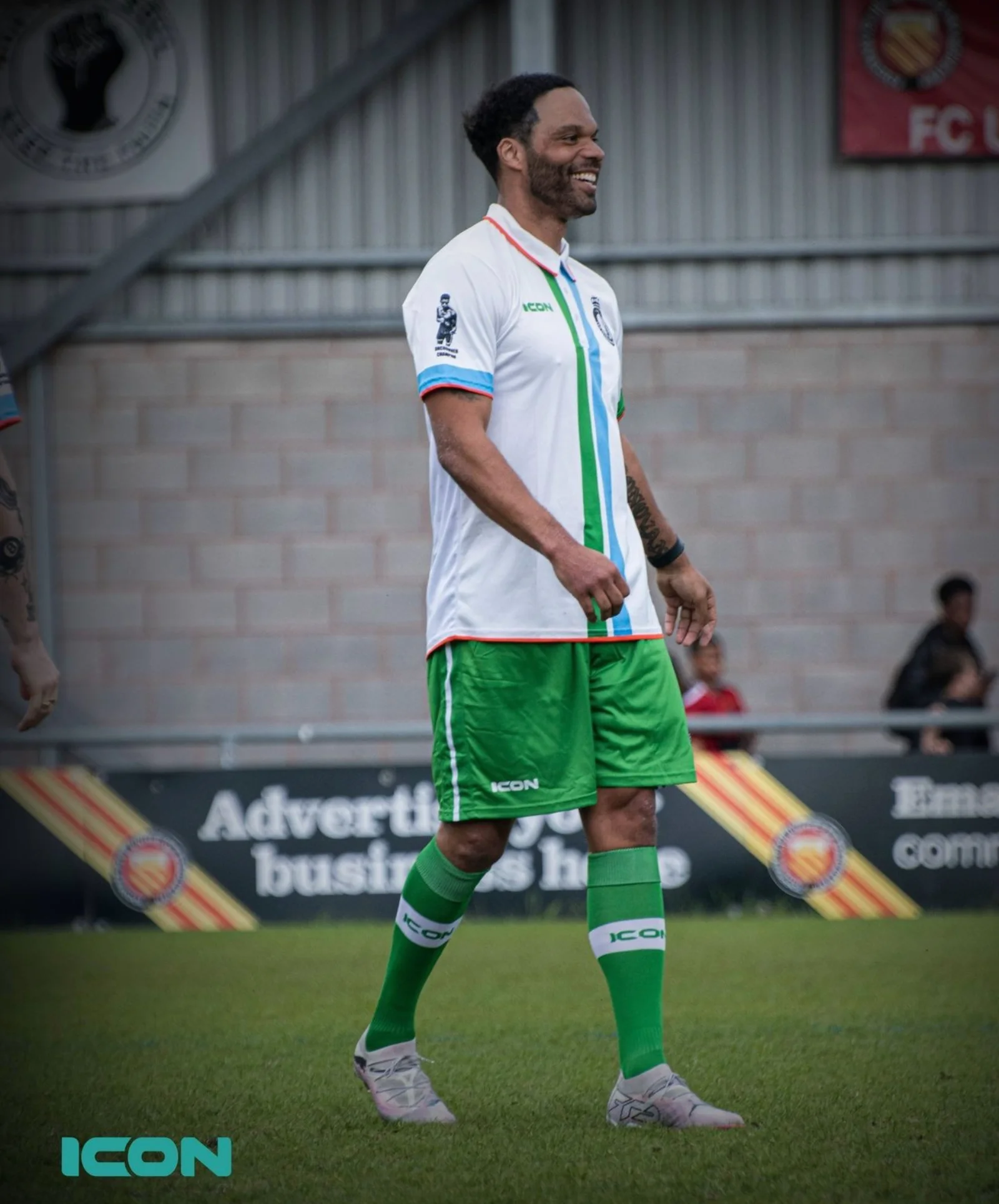 A player in Len Johnson FC All Stars kit walks pitchside, smiling